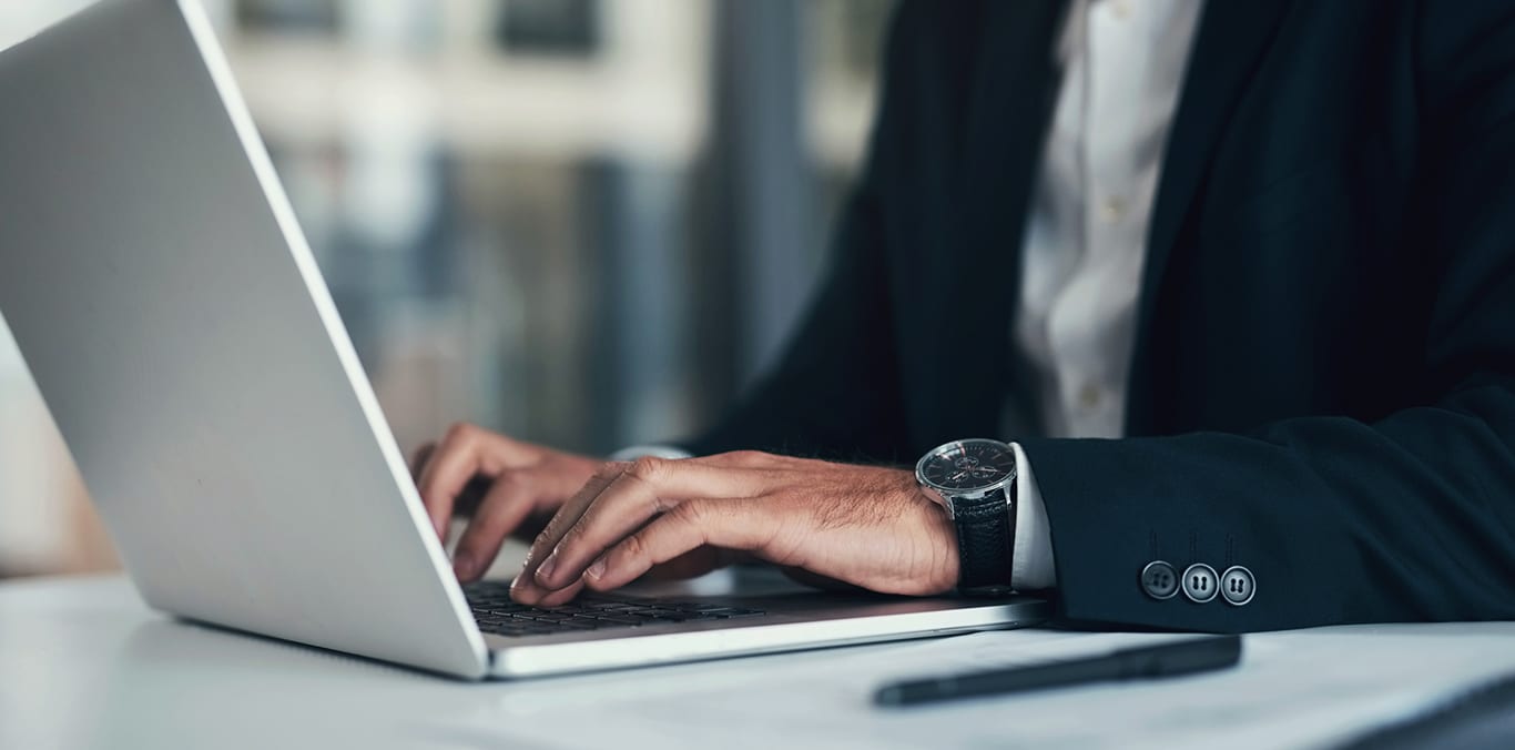 Primer plano de las manos de un sénior trabajando con un ordenador.